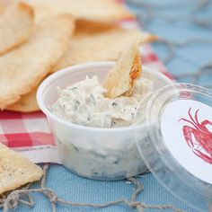 some crackers and dip are sitting on a checkered table cloth next to a bowl of crab dip