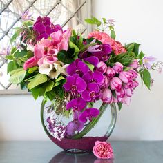 a vase filled with purple and pink flowers on top of a table next to a mirror