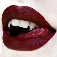 a woman's lips with white teeth and dark red lip glosses on them