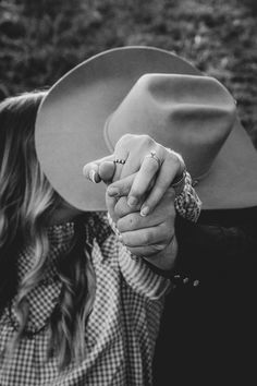 a woman holding the hand of a man wearing a cowboy hat