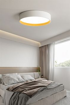 a bedroom with a large bed and a round light above the headboard on the wall