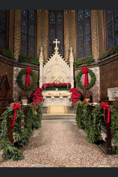 a church decorated for christmas with wreaths on the alter and red bows around it