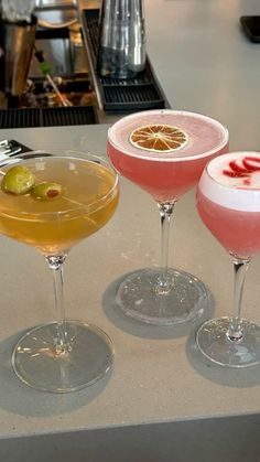 three cocktails sitting on top of a counter next to each other