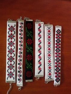 four different types of bracelets are lined up on a wooden table with chains attached to them