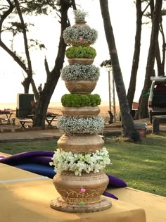 a stack of pots filled with flowers sitting on top of a table next to trees