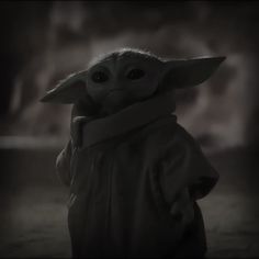 the child yoda from star wars is standing in front of a dark background and looking at the camera