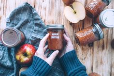 a person holding a jar of peanut butter next to an apple and other food items