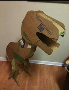 an animal made out of cardboard sitting on top of a wooden floor