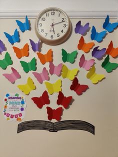 there is a clock on the wall and many colorful butterflies are flying out of an open book