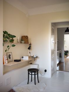 a room with a chair, desk and shelves on the wall next to an open door