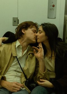 a man and woman kissing on the subway