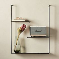 a shelf with two shelves and a radio next to a vase filled with flowers on it