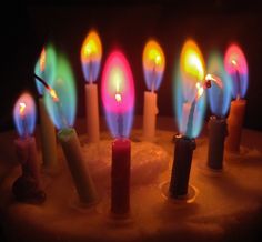 many lit candles are in the middle of a cake with frosting on it and one candle is brightly colored