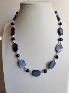 "The oval Mother-of-Pearl beads in this necklace are a medium blue color. It has clear ab Swarovski crystal beads and dark Blue Freshwater pearls. The findings and remaining beads are sterling silver. It is 18\" long and has a 1\" extension with a beaded drop making it adjustable. Custom Orders are always welcome!" Blue Pearl Beaded Necklace With Polished Beads, Blue Pearl Necklaces With Polished Beads, Blue Pearl Necklaces With Gemstone Beads, Blue Pearl Necklace With Polished Beads, Blue Beaded Necklaces With Oval Beads, Blue Oval Beaded Necklaces, Blue Oval Necklaces With Faceted Beads, Blue Oval Necklace With Faceted Beads, Oval Blue Necklaces With Faceted Beads