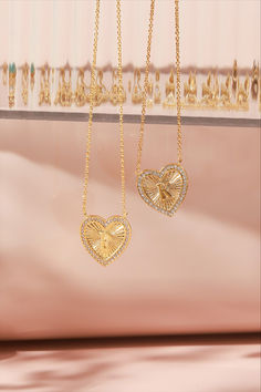 Two gold vintage-inspired heart initial necklaces with an intricate textured pattern and surrounded by small crystals. One heart displays the initial 'P' and the other 'K,' both suspended on a gold chain against a soft pink backdrop. Valentine's Day Initial Pendant Necklace Tarnish Resistant, Tarnish Resistant Initial Pendant Charm Necklace For Valentine's Day, Heart Shaped Monogram Jewelry For Anniversary, Valentine's Day Tarnish Resistant Initial Pendant Charm Necklace, Valentine's Day Tarnish-resistant Initial Pendant Charm Necklace, Vintage Gold Initial Necklace As A Gift, Vintage Gold Initial Necklace For Gift, Vintage Gold Initial Necklace For Gifts, Gold Heart Pendant Initial Necklace For Anniversary