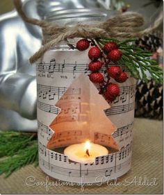 a candle is sitting in a jar with sheet music notes and a christmas tree on it