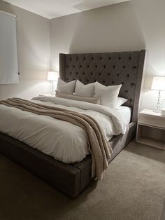 a large bed sitting in the middle of a bedroom next to two lamps on either side of it