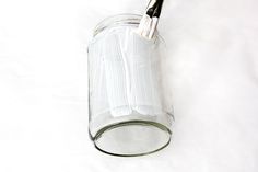 a toothbrush in a glass jar on a white surface