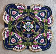 a blue and white square with pink flowers on the center is made out of crochet