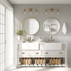 a white bathroom with two mirrors above the sink and three baskets under the vanity area