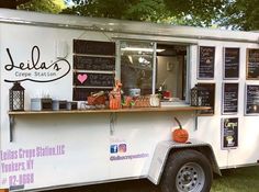 a food truck with chalkboard writing on the side and pumpkins at the counter