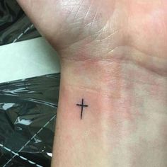 a small cross tattoo on the wrist