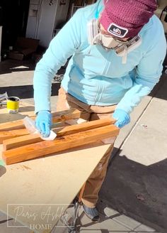 a woman in blue jacket and gloves working on wood