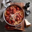 spaghetti with meatballs and parmesan cheese in a pan