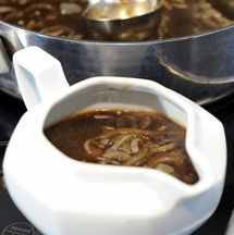 a white bowl filled with soup sitting on top of a stove next to a frying pan