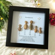 three pebbles are holding hands and standing in front of a frame with flowers