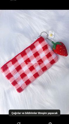 a crocheted red and white purse with a strawberry on the front, attached to a hook