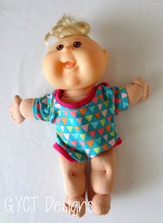 a toy doll with blonde hair and blue shirt laying on the ground next to a white background