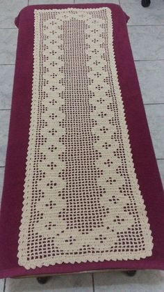 a crocheted table runner sitting on top of a tile floor next to a red rug