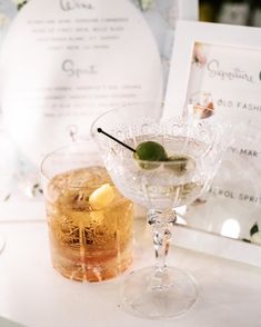 two martinis sitting on top of a table next to a framed photo and menu