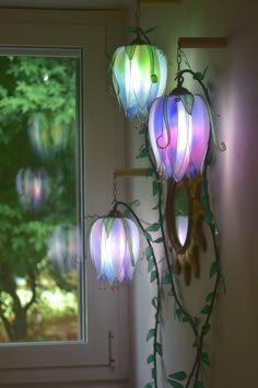 three lights hanging from the side of a wall next to a window with green leaves on it