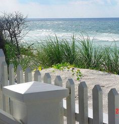 a white picket fence next to the ocean