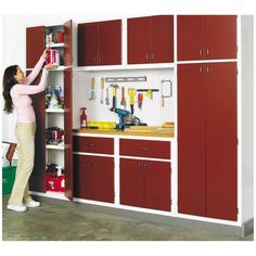 a woman standing in front of a red and white garage shelving unit with tools on it