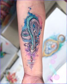 a woman's arm with watercolor tattoos on it and an arrow in the middle