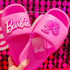 someone is holding up barbie slippers in front of a wall full of pink bubbles