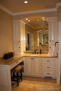 a large bathroom with marble counter tops and white cabinets, along with a bar stool