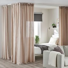 a living room filled with furniture next to a white couch and window covered in curtains