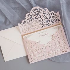 a pink and white wedding card on top of an envelope