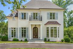 a large white house with lots of windows and shutters on the front door is shown