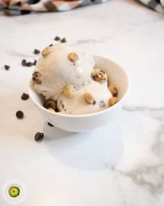 two scoops of ice cream with chocolate chips in a white bowl on a marble counter