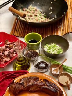 an assortment of food on a table with utensils and sauces in bowls