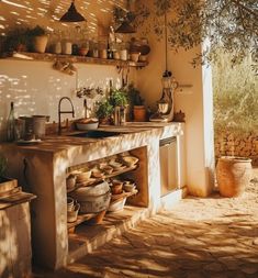 an outdoor kitchen with lots of pots and pans on the stove top, next to a sink