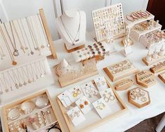 a table topped with lots of jewelry on top of a white cloth covered tablecloth