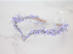 a purple flower crown is sitting on a marble counter top, with beads and flowers in the middle