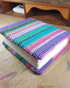 a crocheted book sitting on top of a wooden floor next to a table