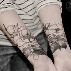 two people with matching tattoos on their arms holding each other's hands and both have flowers on them